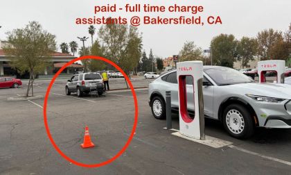 Tesla Supercharger station in Bakersfield, CA showing multiple charging stalls with a silver Tesla Model Y in the foreground, viewed from a three-quarter front angle.