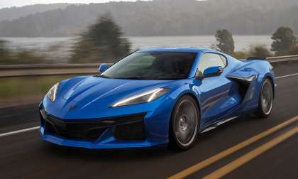 Blue 2023 Chevrolet Corvette Z06 driving on a country road at sunset in a front three-quarter action view.