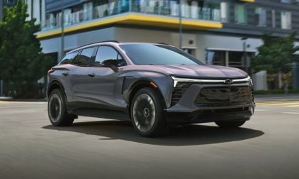 2024 Chevrolet Blazer EV in metallic gray, angled front view, driving past modern urban buildings