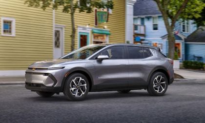 Silver SUV parked on a street with colorful buildings and trees in the background.
