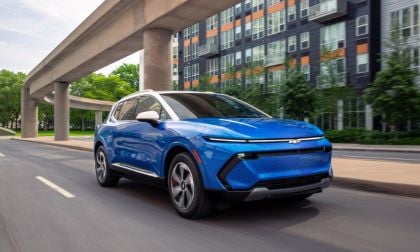 Blue Chevrolet electric SUV driving on urban street beneath elevated highway overpass