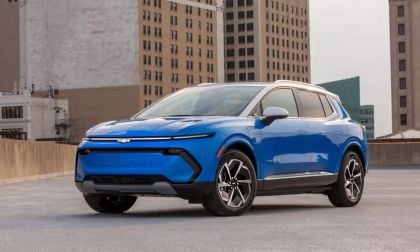 2024 Chevrolet Equinox EV in blue parked on a rooftop, highlighting its sharp electric SUV design, aerodynamic front end, and two-tone accents.