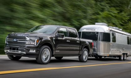 Black 2024 Ford F-150 Platinum towing an Airstream travel trailer, front three-quarter view demonstrating luxury and hauling capability.