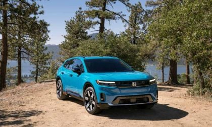 2024 Honda Prologue in bright turquoise blue, front three-quarter view, showcasing sleek LED headlights and modern crossover design, parked on mountain overlook with pine trees and lake vista.