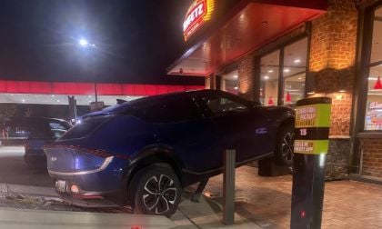 Car partially lifted onto a curbside pickup area, with a tow truck ramp nearby.
