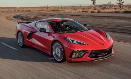 Red Chevrolet Corvette C8 coupe driving at speed on an open desert highway, featuring sharp LED headlights, low-slung stance, and high-performance mid-engine proportions.