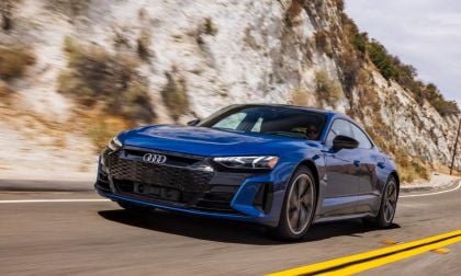Blue Audi e-tron GT driving on mountain road with white limestone cliffs behind