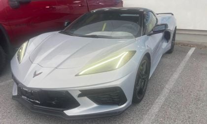 2023 Chevrolet Corvette C8 in Arctic White, front three-quarter view, featuring angular LED headlights and aggressive black front splitter, parked in covered lot.