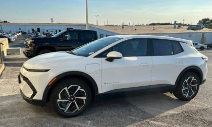 White SUV parked in a lot, with a black truck in the background.