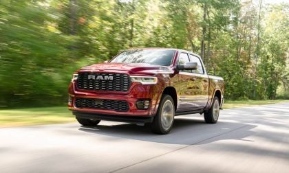 Candy apple red RAM pickup truck speeding down a tree-lined road with motion blur and gleaming chrome details
