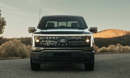 Front view of a Ford truck on a road with hills and shrubs in background.