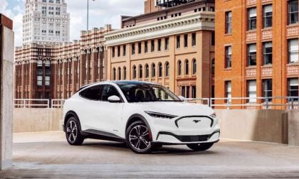 White Ford Mustang Mach-E electric SUV parked on urban rooftop with historic brick buildings in background