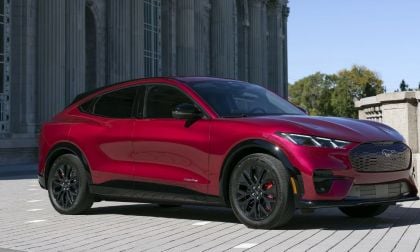 Candy apple red Ford Mustang Mach-E electric SUV parked on stone pavement near neoclassical architecture
