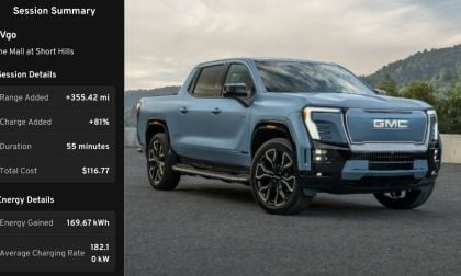 A blue GMC electric truck parked in a scenic area, displaying charging session details, including range, charge, time, and cost.