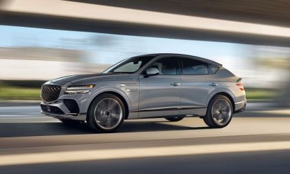 Silver Genesis GV80 SUV in motion, showcasing dynamic side profile with blurred urban background