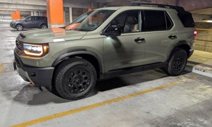 2025 Honda Passport TrailSport in olive green, side view in parking garage, featuring black off-road wheels, LED headlights, and rugged all-terrain tires.