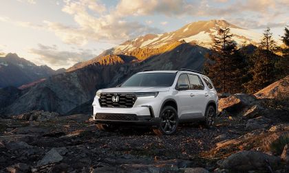 2025 Honda Pilot Black Edition SUV parked on a rocky mountain overlook with snow capped peaks behind it