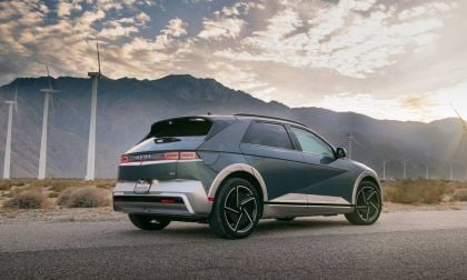 A Gray 2025 Hyundai Ioniq 5 parked on a road with wind turbines and a mountainous backdrop under a partly cloudy sky.