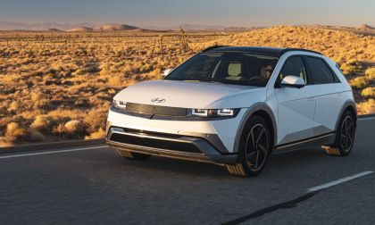 White Hyundai IONIQ 5 electric SUV driving on desert highway at golden sunset with mountains