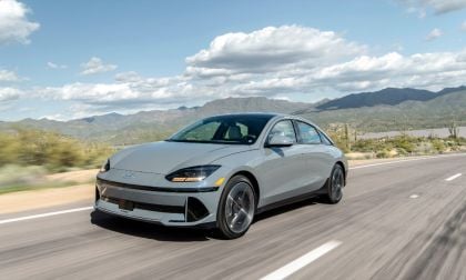 Silver 2025 Hyundai Ioniq 6 driving on desert highway with mountain backdrop, aerodynamic profile and modern design