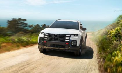 White Hyundai Tucson driving on dusty coastal road with blurred greenery and ocean horizon