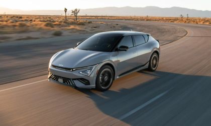 2025 Kia EV6 electric SUV front three-quarter view driving on desert highway at sunset.