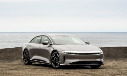 Silver Lucid Air electric luxury sedan parked on coastal terrain against ocean backdrop