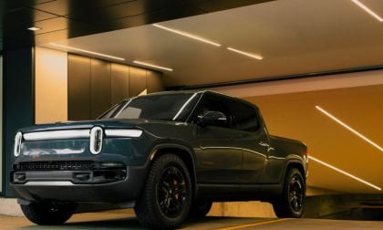 A dark green electric pickup truck parked in a modern, well-lit garage.