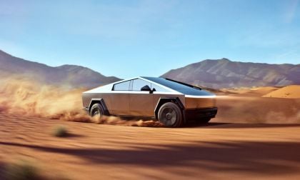 Tesla Cybertruck shown in side profile, kicking up dust while driving through desert terrain with mountains in background, showcasing its distinctive angular stainless steel design.