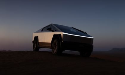 A futuristic electric truck, Tesla Cybertruck, stands on a desert dune at dusk, silhouetted against a twilight sky.