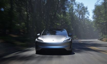 2025 Tesla Model 3 Performance in silver, driving dynamically on a forested mountain road with blurred motion background