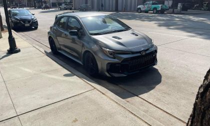 2025 Toyota GR Corolla in metallic gray, parked on urban concrete sidewalk with aggressive stance and black wheels