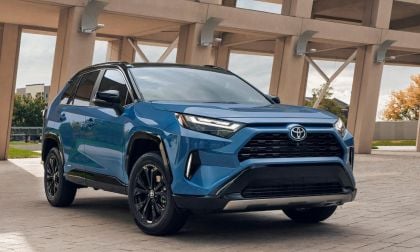 2025 Toyota RAV4 Prime in metallic blue, front three-quarter view, featuring black wheels and aggressive front fascia, parked under modern architectural columns.
