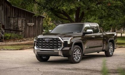 2023 Toyota Tundra Limited in dark brown, front three-quarter view, featuring chrome honeycomb grille and LED headlights, parked near rustic pottery barn.