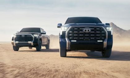 Two Toyota Tundras drive through a dusty desert landscape. The trucks, one gray and one blue, are side by side, projecting power and ruggedness.