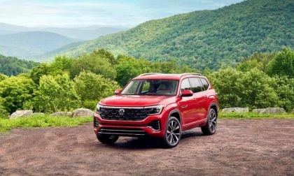 Red SUV parked on a dirt road with lush green hills in the background.