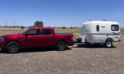 Red Ford Maverick towing a small Casita travel trailer in a full side view.