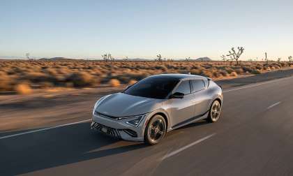 Gray 2025 Kia EV6 driving on a desert highway in a front three-quarter action view.