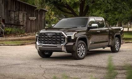 Smoked Mesquite 2025 Toyota Tundra 1794 Edition parked near a rustic building in a front three-quarter view.