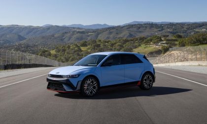 2025 Hyundai IONIQ 5 N in Performance Blue Matte on racetrack, front three-quarter view with mountains and green hills in background