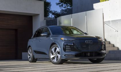 2024 Audi Q4 e-tron in metallic gray, front three-quarter view, parked on modern concrete driveway with geometric white walls.