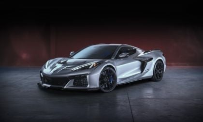 Silver 2024 Chevrolet Corvette Z06 sports car, front three-quarter view, featuring aggressive aerodynamics, rear wing, black wheels, studio setting.