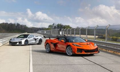 Orange and silver Chevrolet Corvette Z06 sports cars parked on racetrack behind safety fence
