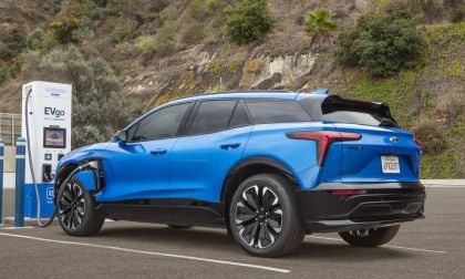 A blue 2026 Chevrolet Blazer EV is charging at an EVgo fast charging station amid a hilly landscape with greenery in the background.
