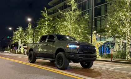 2026 Dodge Ram pickup truck in matte green parked on illuminated city street at night with modern buildings and decorative lights