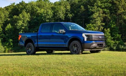 Blue Ford F-150 STX pickup truck parked on grass with forest backdrop