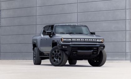 Gray electric Hummer truck parked in front of a large concrete wall.