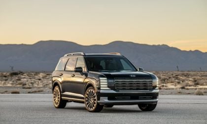 Black 2024 Hyundai Palisade, SUV, front three-quarter view, featuring gold multi-spoke wheels and white racing stripes, photographed in desert landscape at sunset.