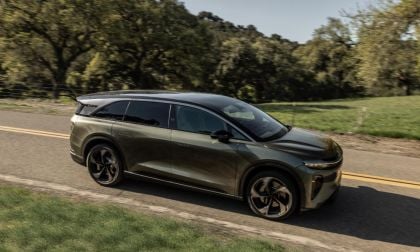 2025 Lucid Gravity in black, photographed from 3/4 front angle on winding rural road, featuring black wheels and performance styling.