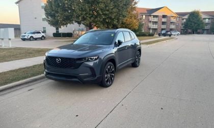2026 Mazda CX-50, in metallic blue, side profile view, featuring black trim, distinctive two-tone alloy wheels, parked outside dealership.